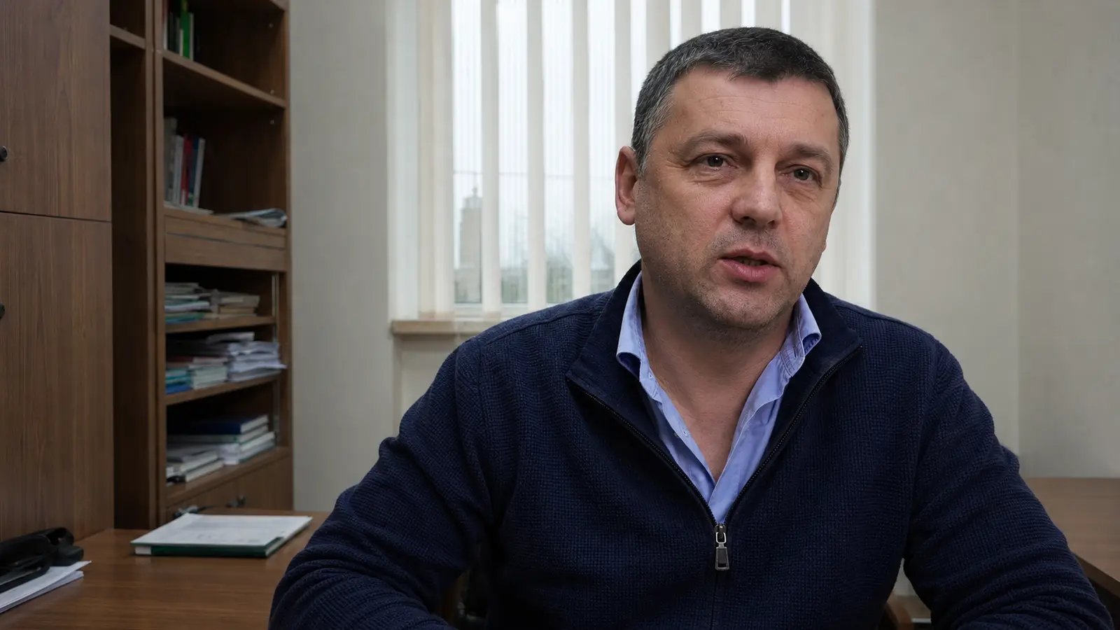 Более широкий объектив с той же позиции даёт рабочий средний план героя в кабинете